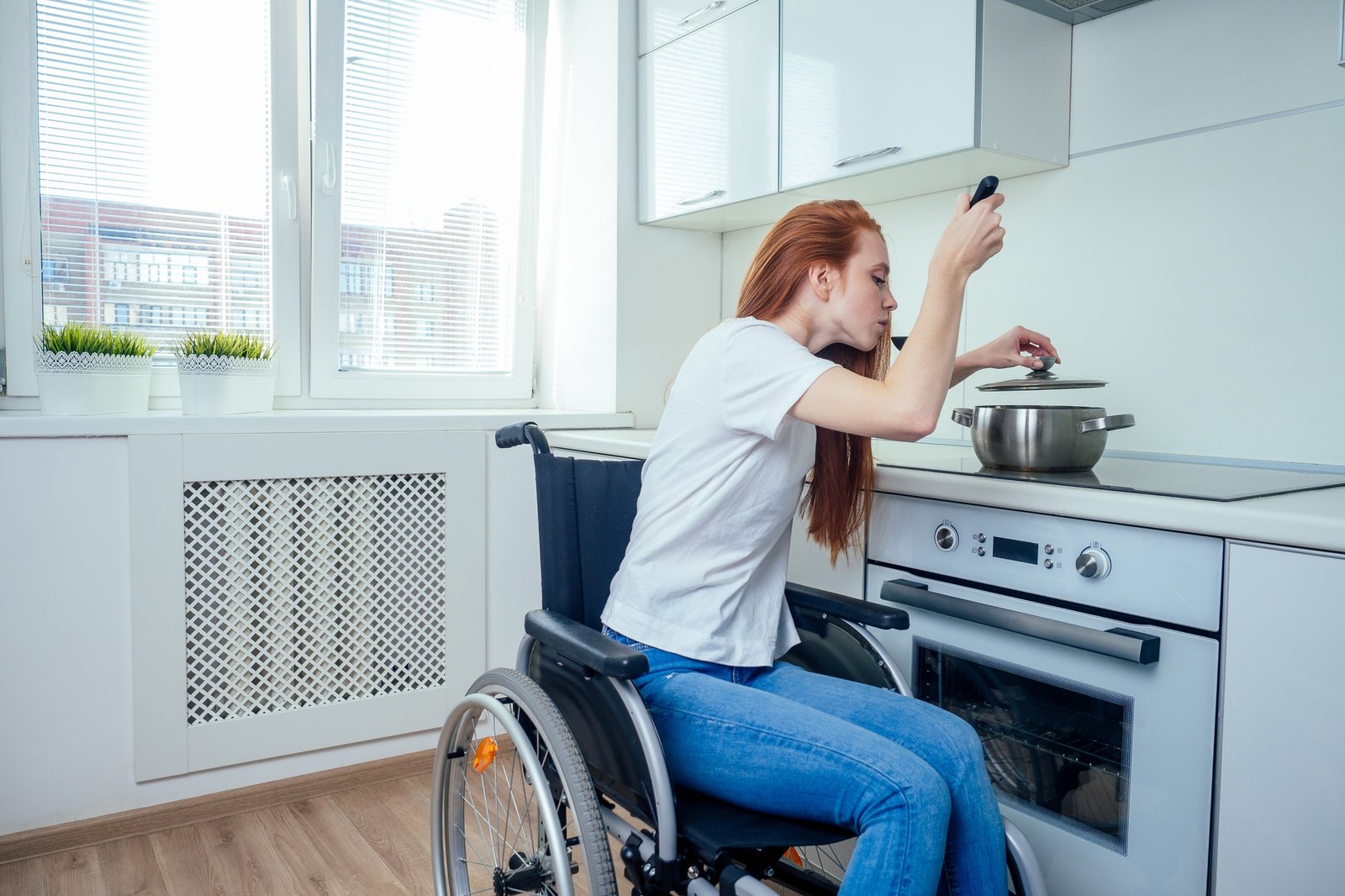 disabled redhaired ginger woman in wheelchair preparing meal in kitchen