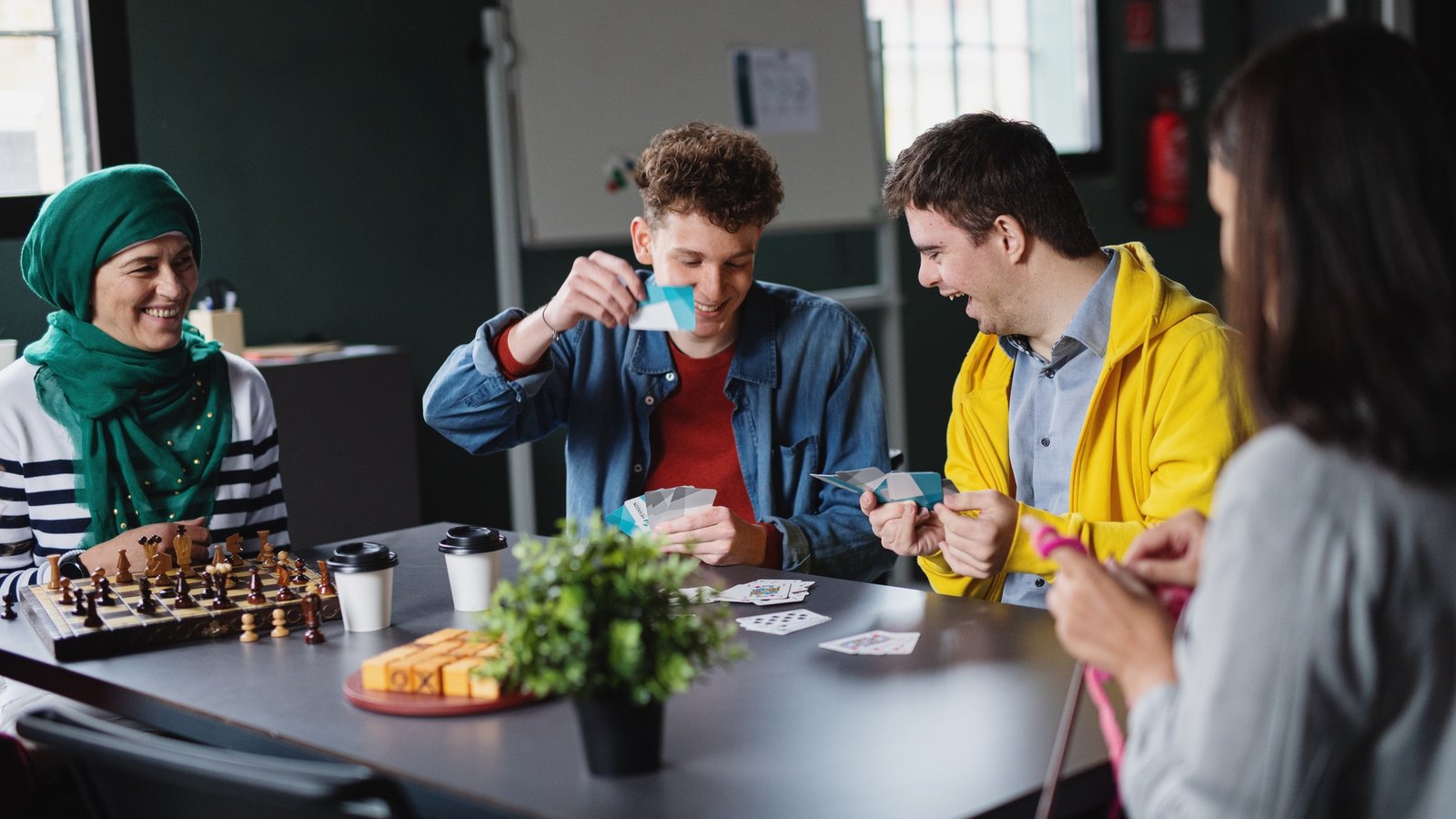 Group of people playing cards and board games in community center, inclusivity of disabled person