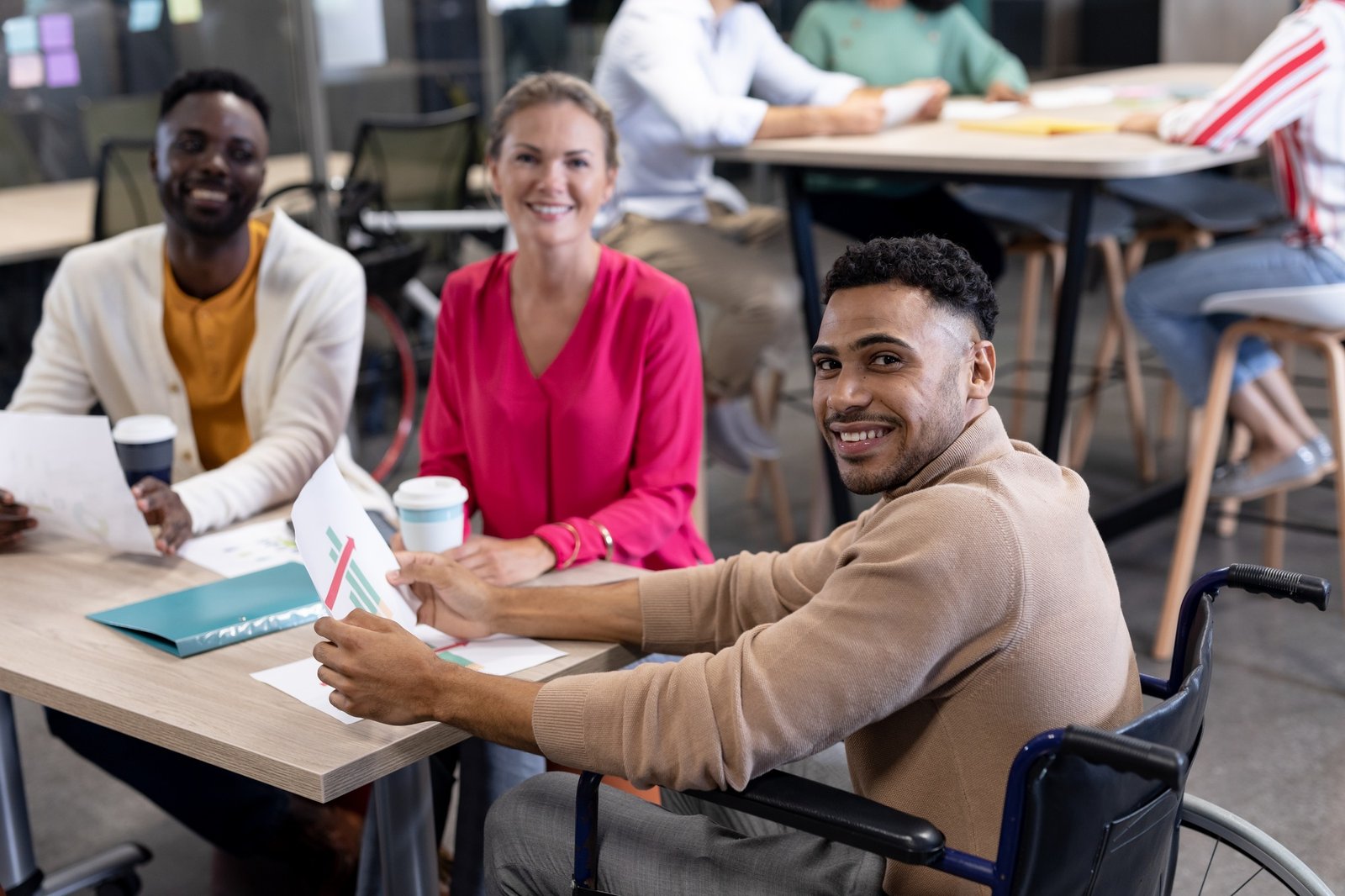 Portrait of hispanic disabled businessman with biracial colleagues in meeting at workplace